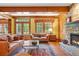 Inviting living room featuring stone fireplace, wooden beams, and large windows with a seating area at 1700 E Tufts Ave, Cherry Hills Village, CO 80113