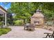 Outdoor patio with a stone fireplace, dining table with chairs, and lush landscaping at 1700 E Tufts Ave, Cherry Hills Village, CO 80113