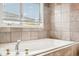 Close-up of a relaxing tub with chrome fixtures and a window with blinds at 5058 E Cherry Creek South Dr, Denver, CO 80246