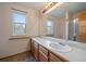 Bright bathroom featuring a double sink vanity, large mirror, and a shower with glass door at 11539 Depew Ct, Westminster, CO 80020