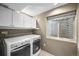 Functional laundry room with modern washer and dryer units, efficient storage cabinets, and a window for natural light at 2393 Yosemite St, Denver, CO 80238