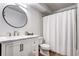 Bright bathroom with white vanity, round mirror, and shower with curtain at 10150 E Virginia Ave # 19-102, Denver, CO 80247