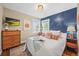 Stylish bedroom with a blue accent wall, hardwood floors, and an abundance of natural light at 4456 S Washington St, Englewood, CO 80113