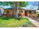 Charming brick home with a red door, lush lawn and mature tree offering a welcoming curb appeal at 4456 S Washington St, Englewood, CO 80113