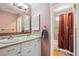 Bathroom with double vanity, neutral countertop, and shower with colorful curtain at 9532 W Walden Ave, Littleton, CO 80128