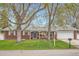 Charming red brick ranch with a blue front door, lush lawn, and mature trees in a desirable neighborhood at 9580 W 12Th Pl, Lakewood, CO 80215