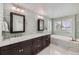 Luxurious bathroom with double vanity, decorative tile backsplash, marble floors, and a soaking tub under shuttered windows at 6526 N Windfield Ave, Parker, CO 80134