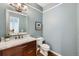Powder bathroom with a wood vanity, marble top, and framed mirror at 6526 N Windfield Ave, Parker, CO 80134