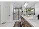 Modern bathroom featuring a double vanity with wood cabinets and a glass-enclosed shower with black trim at 9140 Moondance Dr, Littleton, CO 80125