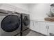 Modern laundry room with gray front-loading washer and dryer and white cabinets at 9140 Moondance Dr, Littleton, CO 80125