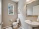 Bright powder room featuring a pedestal sink, toilet, and window for natural light at 2820 Macon Way, Denver, CO 80238