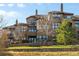 Multi-story home featuring multiple balconies and lots of windows overlooking a green lawn and rock wall at 7882 Vallagio Ln, Englewood, CO 80112