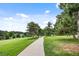Scenic view of a paved pathway winding through a lush green golf course with mature trees at 7882 Vallagio Ln, Englewood, CO 80112