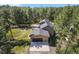 Aerial view of home with a large garage, basketball hoop, patio with furniture, and is surrounded by evergreen trees at 11044 Conestoga Pl, Franktown, CO 80116