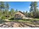 The back exterior of the home with a basketball hoop surrounded by trees at 11044 Conestoga Pl, Franktown, CO 80116