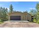 Attached two-car garage with dark wood doors and durable concrete driveway surrounded by natural landscape at 11044 Conestoga Pl, Franktown, CO 80116