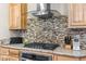 Close up of kitchen with custom wood cabinetry, stainless steel appliances, and glass tile backsplash at 11044 Conestoga Pl, Franktown, CO 80116