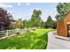 Serene backyard features a lush lawn, mature trees, and a charming pergola, creating a private outdoor oasis at 1997 Fox Haven Dr, Castle Rock, CO 80104