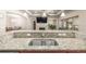 Open kitchen with granite countertops, stainless steel sink, and view into Gathering room and dining area at 19407 E Radcliff Pl, Aurora, CO 80015