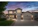 Charming two-story home with a well-maintained lawn, covered porch, and a two-car garage at dusk at 12032 Triple Crown Dr, Parker, CO 80134