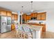 Bright kitchen features an island with seating, wood cabinets, and stainless steel refrigerator at 12032 Triple Crown Dr, Parker, CO 80134