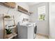 Functional laundry room featuring a washer, dryer, storage shelves, and a window at 12032 Triple Crown Dr, Parker, CO 80134