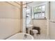 Apartment bathroom with vintage fixtures, a clawfoot tub, and white tiled walls illuminated by natural light from the window at 215 E 11Th Ave # B9, Denver, CO 80203