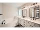 Updated bathroom with tub, dual sinks, and modern mirrors at 10707 W Cooper Dr, Littleton, CO 80127