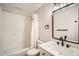 Bathroom with tub/shower combination featuring white tile and dark hardware at 10707 W Cooper Dr, Littleton, CO 80127