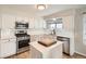 Updated kitchen features white cabinets, stainless steel appliances, island with white countertop and wood floors at 10707 W Cooper Dr, Littleton, CO 80127
