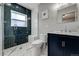 Modern bathroom with blue tile shower, glass door, stylish marble floors, and elegant vanity at 4790 E Dartmouth Ave, Denver, CO 80222