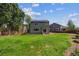 The backyard features a well-manicured lawn, trees, and a two-story green home with solar panels at 12702 E 105Th Ave, Commerce City, CO 80022