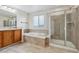 Bright bathroom featuring a soaking tub, a large shower with glass doors, and wooden cabinets at 12702 E 105Th Ave, Commerce City, CO 80022
