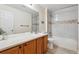 Bathroom with wood cabinets, large mirror, and a tub/shower combo with a white tiled surround at 12702 E 105Th Ave, Commerce City, CO 80022