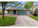 Charming two-story home featuring a covered porch, lush lawn, and an attached two-car garage at 12702 E 105Th Ave, Commerce City, CO 80022