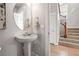Stylish powder room featuring pedestal sink, round mirror, and hardwood floors continuing up staircase at 2521 N Xenia St, Denver, CO 80238