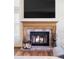 Close-up of a fireplace featuring brick surround, wood mantle, and a burning fire at 9867 W Berry Dr, Littleton, CO 80123