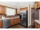 Open kitchen features wood cabinets, stainless steel appliances, tile backsplash and bright window at 9867 W Berry Dr, Littleton, CO 80123