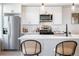 Well-lit kitchen with stainless steel appliances, white cabinets, and a breakfast bar with seating at 2900 W Parkside Pl, Denver, CO 80221