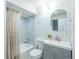 Well-lit bathroom featuring a tub with shower, grey vanity, and round mirror at 5041 S Julian St, Englewood, CO 80110