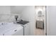 Functional laundry room with modern washer, dryer and a view to the bathroom at 5041 S Julian St, Englewood, CO 80110
