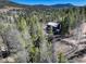 Aerial view of the mountain home surrounded by lush green trees and a blue sky at 12229 Circle Dr, Conifer, CO 80433