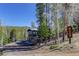 Mountain home with a deck and rustic exterior, nestled among trees and a blue sky at 12229 Circle Dr, Conifer, CO 80433
