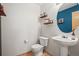 Cozy half bathroom with stylish round mirror, pedestal sink, and decorative wall shelves at 6190 Sparrow Ave, Firestone, CO 80504