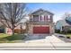 Charming two-story home with gray siding, brick accents, red garage door, and red shutters on a sunny day at 6190 Sparrow Ave, Firestone, CO 80504