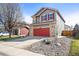 Two-story home featuring grey siding, brick accents, red garage door and shutters on a well-kept lawn at 6190 Sparrow Ave, Firestone, CO 80504