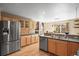 Bright kitchen with stainless steel appliances, wood cabinets, and a dining area view at 6190 Sparrow Ave, Firestone, CO 80504