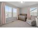 Sunlit bedroom featuring a wood crib, comfortable chair, and multiple windows at 74 Lullaby Ln, Castle Rock, CO 80109