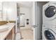 Bright bathroom featuring double sinks, a glass-enclosed shower, and a convenient stacked washer and dryer at 2325 Walnut St # 4, Denver, CO 80205