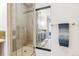 Bathroom showcasing a glass shower, neutral tile, a framed mirror, and a view into another room at 2325 Walnut St # 4, Denver, CO 80205